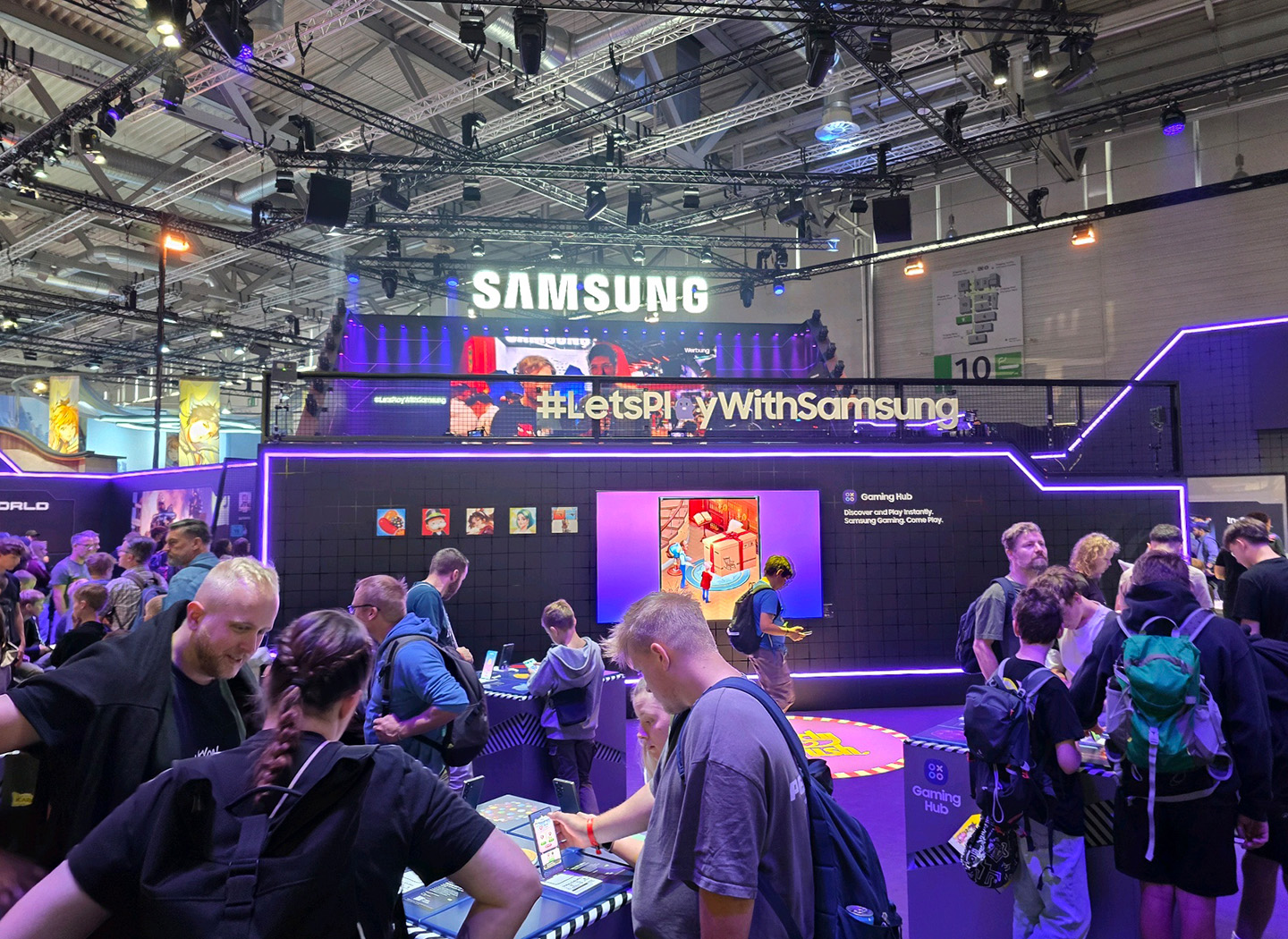 The Samsung booth featuring a digital backdrop with people gathered around the experience stands.