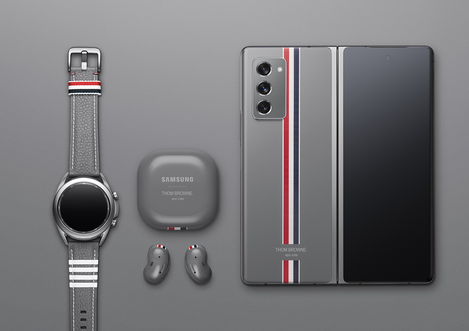 Galaxy Z Fold2/Galaxy Watch3,/Galaxy Buds Live Thom Browne Editions on grey surface. Wide.