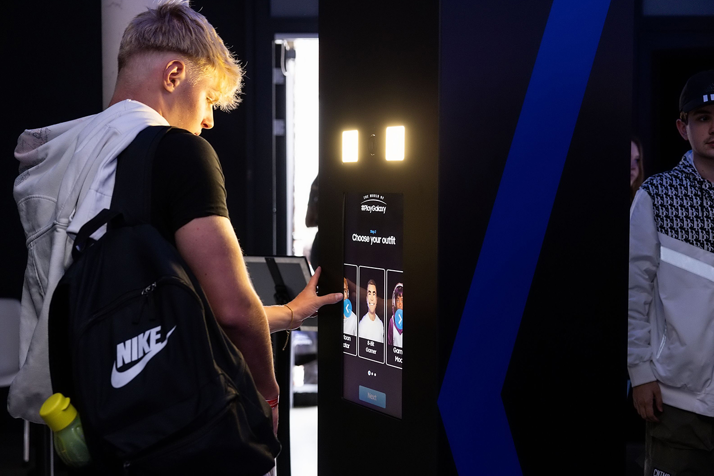 A young man stands at the entrance to The World of PlayGalaxy venue, making selections on a digital screen.