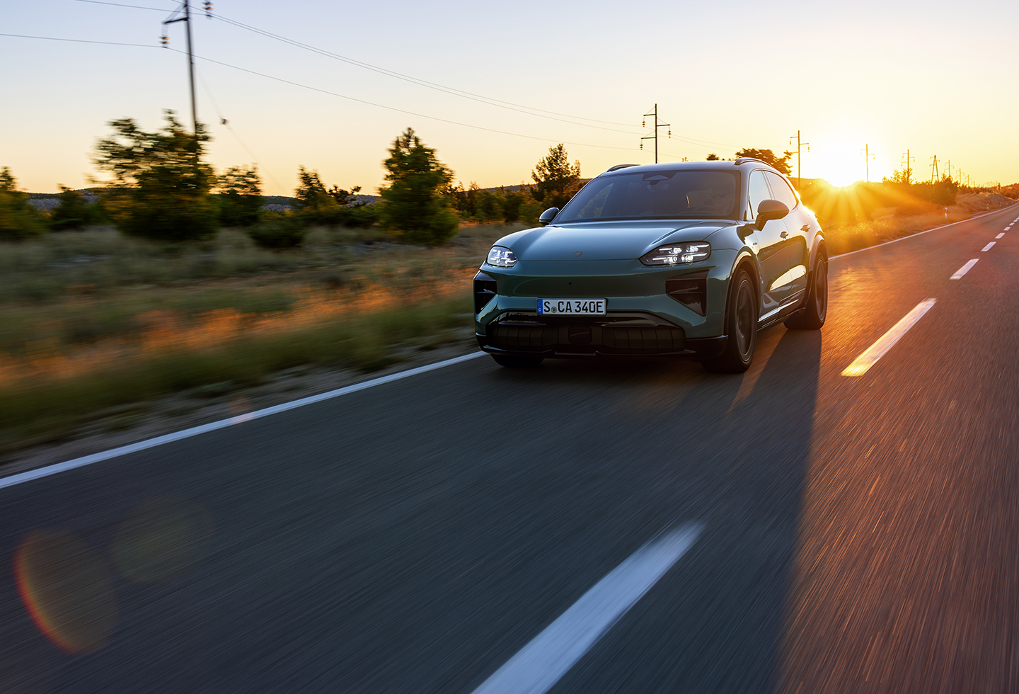 Un carrusel de imágenes muestra el Porsche Macan 2026 en Carmine Red y el Porsche Cayenne Electric en Mystic Green, ambos en la carretera. 